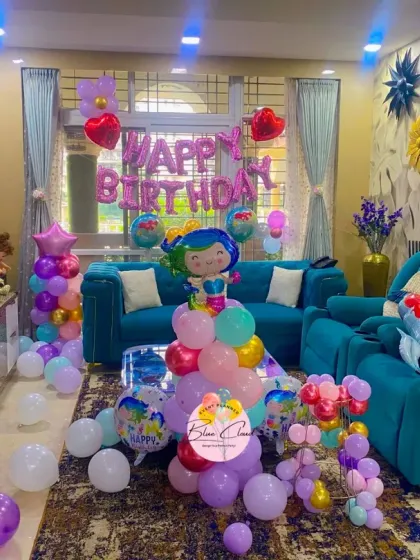 A mermaid-themed birthday decoration spread across a living room, with character balloons and 'Happy Birthday' foils.