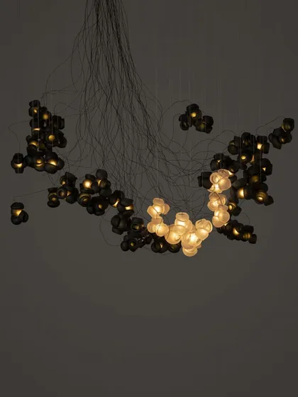 A full view of the custom Bocci 100 chandelier against a dark background. The arrangement appears as a constellation of light, a testament to the fixture's versatility and artistic impact.