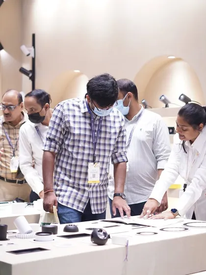 A group of attendees gathers around a product display, examining the fine details of modern lighting components.