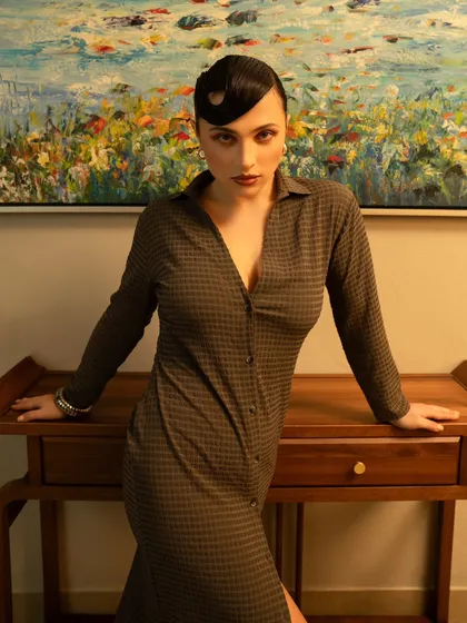 A sophisticated look for a contemporary brand, shot indoors to create a warm, lived-in feel. The styling and the model's pose exude a quiet, confident elegance.