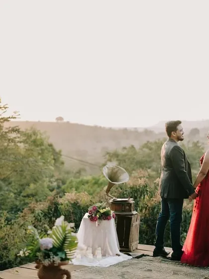 A breathtaking wide shot of a couple against a valley backdrop at sunset, with a vintage gramophone adding a touch of timeless romance to their pre-wedding shoot.