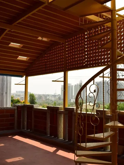A rooftop terrace with a jaali wall and a spiral staircase, offering panoramic views of the city while maintaining a sense of privacy and connection to the home.