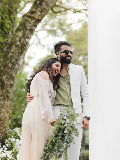 Sharing a laugh and a quiet moment together. Midhun and Anjana's natural chemistry shines in this candid shot from their beautiful outdoor wedding celebration.