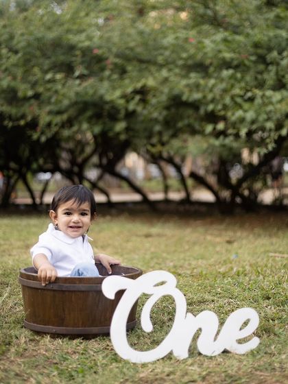 A sweet smile from a wooden bucket prop, with the "One" sign marking his first birthday.