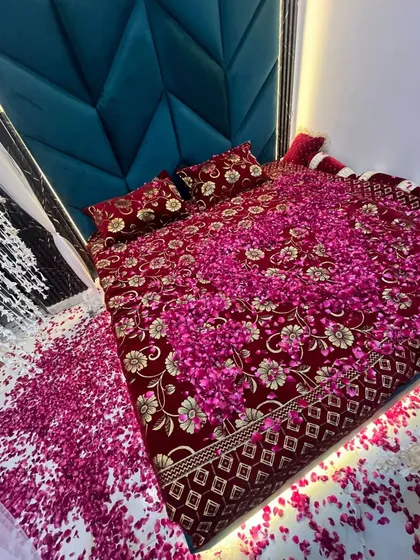 An overhead view of the bed completely covered in a thick layer of pink rose petals for a luxurious and romantic first night setup.