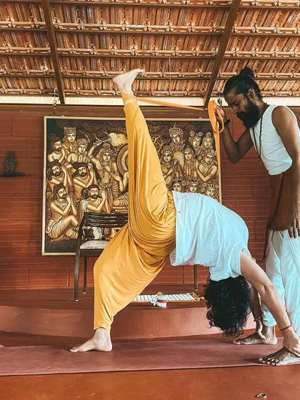 Here, I assist a student in a one-legged downward dog split, helping them to open their hip while keeping the shoulders square. This level of refinement is a focus of the 300-hour course.