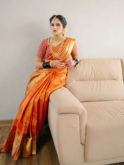 A full view of bride Archana in her orange Kanjeevaram saree. The rich color of the silk is beautifully balanced by the custom-designed blouse.