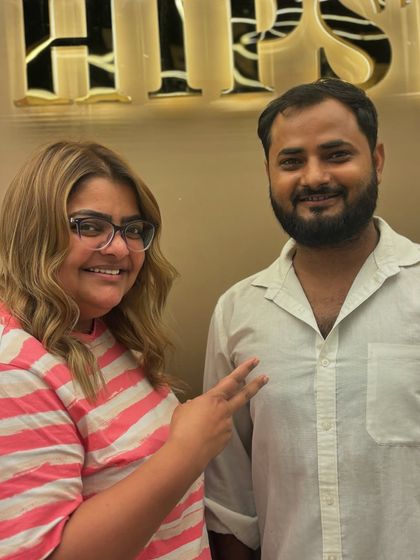 A happy client posing with her stylist after her color transformation. Her smile and peace sign show how thrilled she is with her new look.