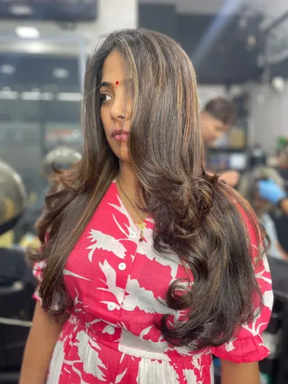 This client is rocking a layered haircut with voluminous curls, creating a glamorous and eye-catching style that is full of life.