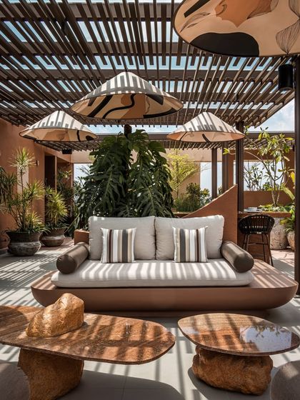 A daytime detail of the custom-built seating and sculptural coffee tables. The organic shapes and earthy materials are chosen to complement the natural elements of the garden design.