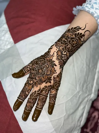 An example of a full-coverage floral design, perfect for a bride's family or for any grand celebration. The pattern features detailed rose motifs and delicate leaf vines covering the hand and arm.