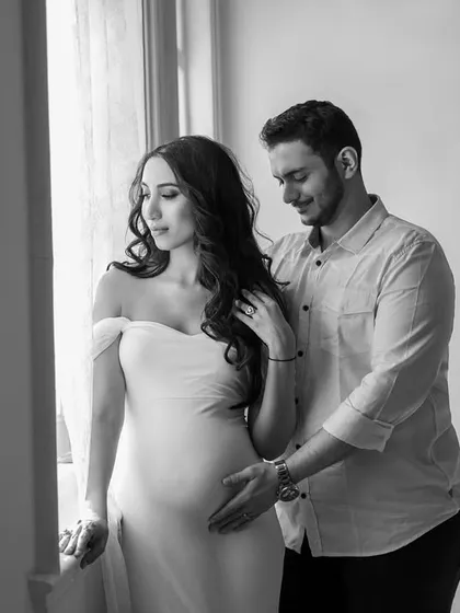 A tender moment by the window. Natural light creates a soft, romantic mood in this black and white couple portrait, highlighting their gentle connection.