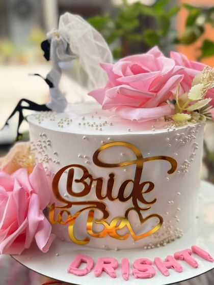 A chic "Bride to Be" cake with pink roses and a stylish topper.