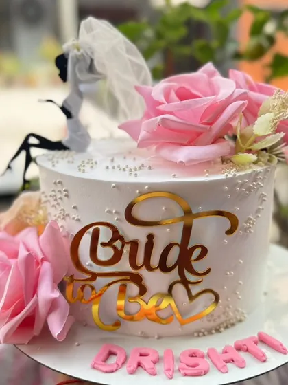 A chic "Bride to Be" cake with pink roses and a stylish topper.