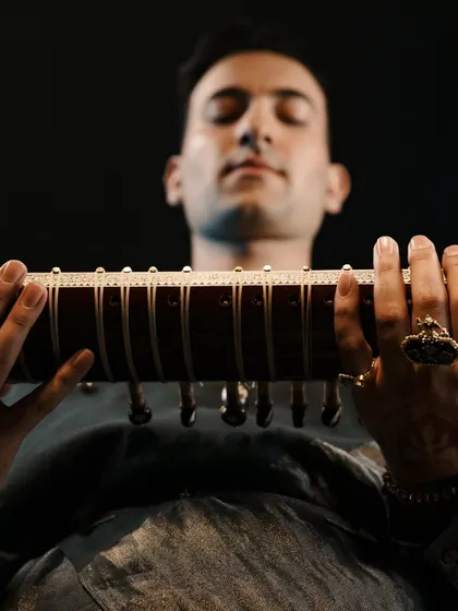 A close-up of the sitar, with my hands and a custom ring in focus. The details matter, from the jewelry to the henna.