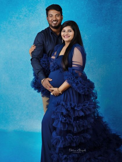 A happy and confident couple's portrait. The rich blue of her gown and the matching backdrop create a cohesive and striking image.