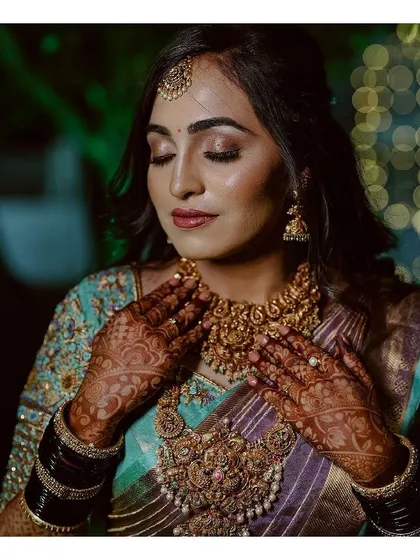A moment of quiet reflection. This shot beautifully captures the intricate henna, the stunning temple jewelry, and the flawless, soft-focus makeup that brings the entire bridal look together.