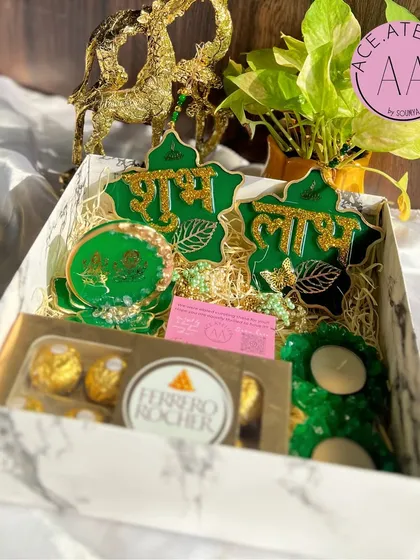 A look inside my green-themed Diwali hamper. This set includes a resin Lakshmi Ganesh standee, matching Shubh Labh hangings, and floral t-light holders, all nestled in a marble-finish gift box.
