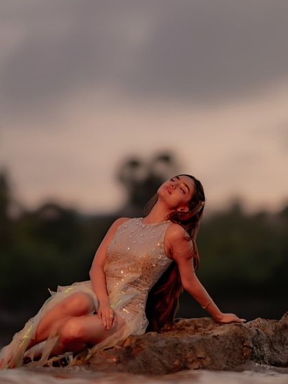 A serene moment from Anushka Sen's music video. The soft evening light catches the sequins on her dress, creating a beautiful, shimmering effect against the rocks.
