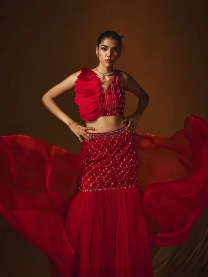 A dramatic, wide-angle shot of a red lehenga from Label Japji Arora, with the organza dupatta creating a sense of movement.