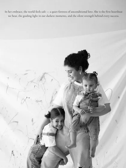 A mother's embrace is a fortress of unconditional love. This candid moment from a 'Mom & Me' paint session captures the quiet strength and gentle bond between a mother and her children, preserved in a classic black and white photograph.