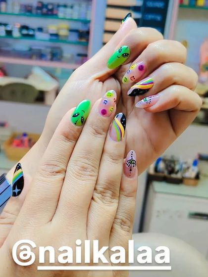 A quirky and colorful "trippy" nail art set. This design features hand-painted aliens, rainbows, and evil eye symbols on a clear base for a fun, eclectic look.