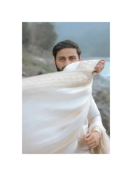 An artistic portrait of the groom in Rishikesh, with his white scarf flowing in the wind against the backdrop of the turquoise Ganga.