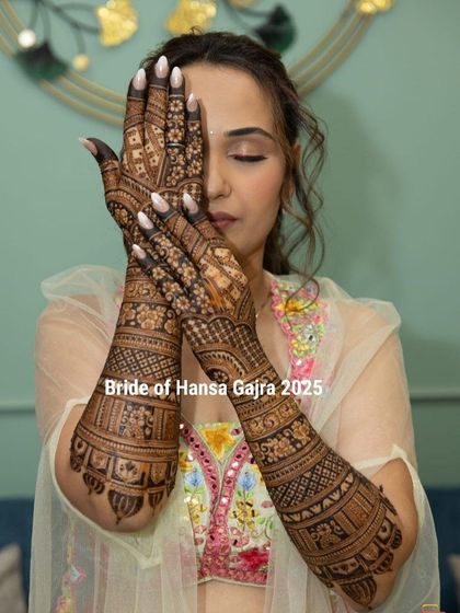 A beautiful bride showcasing her full-arm traditional mehendi. Her confident and serene pose highlights the intricate details and the journey from photo prints to digital media.