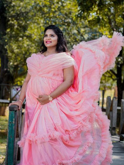 A radiant solo portrait on a wooden bridge. The soft pink gown flows beautifully, and the natural, diffused light creates a flattering and dreamy look.