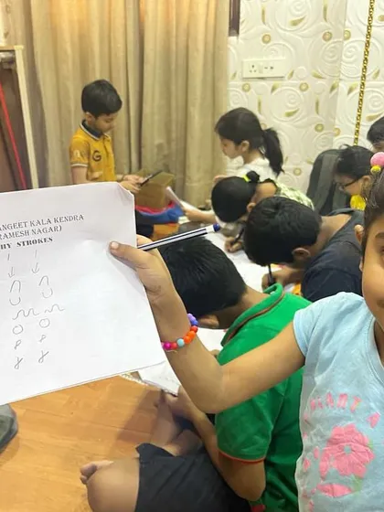 A young student proudly shows her calligraphy practice sheet. It’s all about starting with the basics and building from there.