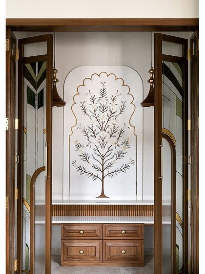 This gorgeous Puja Room features a custom marble inlay wall depicting the tree of life. The intricate design is framed by custom wooden doors with tinted, patterned glass.