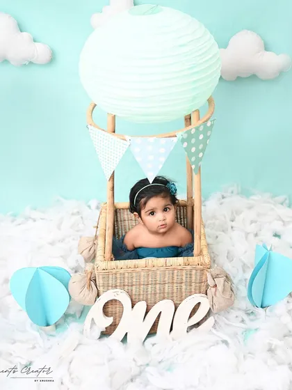Up, up, and away! This sweet baby girl is ready for an adventure in her very own hot air balloon. This whimsical setup is a creative and beautiful way to mark a first birthday.