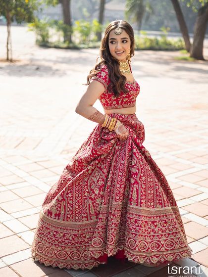 A full shot of the bride twirling in her red lehenga. The makeup is designed to look stunning in motion.