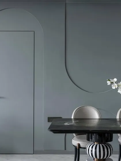 The 'House of Arcs' lives up to its name with curves and arches integrated throughout the design. Here, a flush door is set within a wall featuring decorative arched grooves, creating a subtle yet cohesive design language.