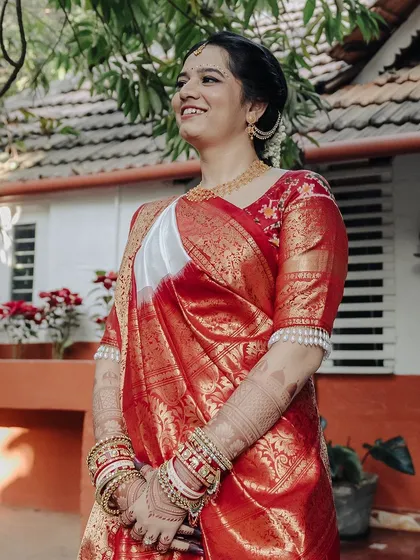 A serene outdoor shot of the bride in her beautiful red and white saree, looking absolutely graceful.