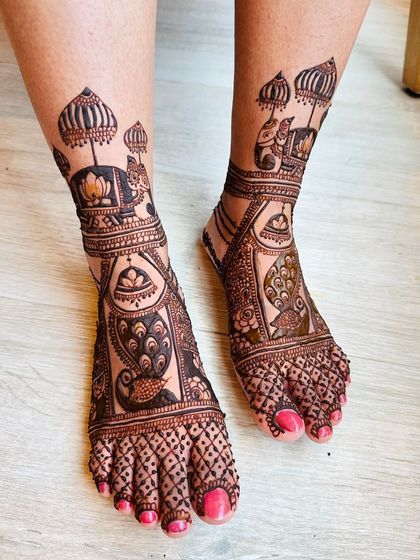 A stunningly detailed foot design featuring peacocks, elephants, and lotus flowers, created to match the bride's intricate hand mehndi for a complete look.