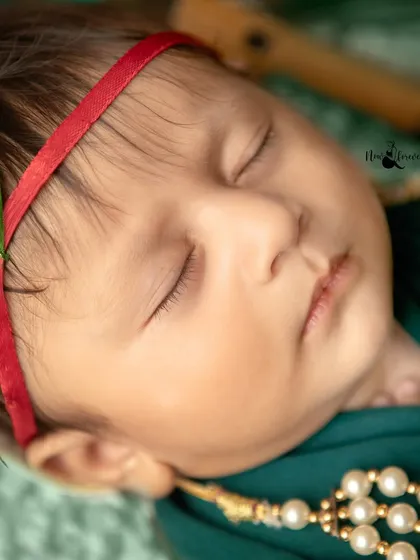A detailed close-up of the newborn's face, with a peacock feather in his headband. This shot highlights the delicate features and the essence of the Krishna theme.