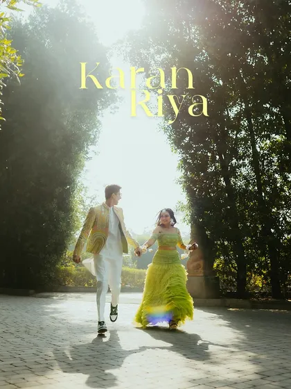 A dreamy, backlit shot of the couple running hand-in-hand through a tree-lined path during their Haldi event.