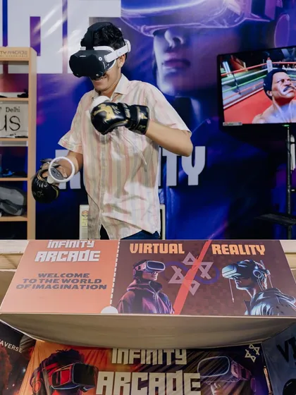 Ready to box in the virtual ring! This player is using VR boxing gloves for a more realistic and active gaming session. The spectator screen behind him shows his opponent.