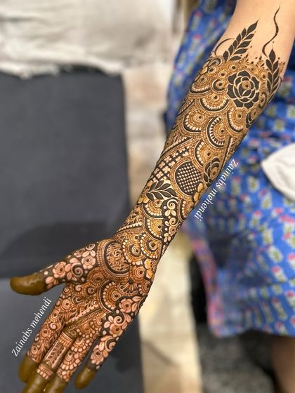 A full arm design for bride Nida, featuring a bold black rose at the elbow and a cascade of intricate patterns down to the fingertips.