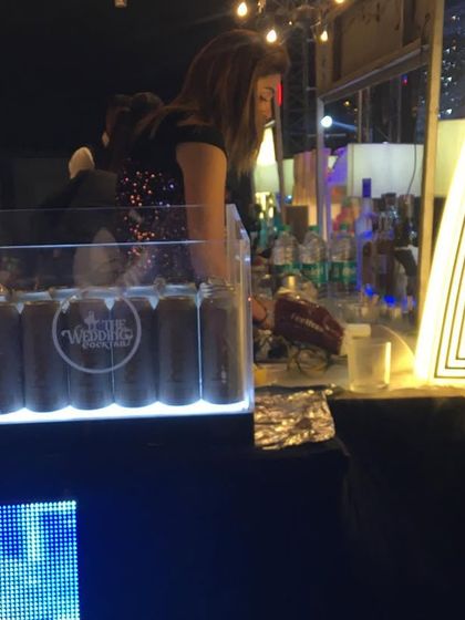 A bartender serving at a themed event, with our custom 'TWC' light-up decor piece prominently displayed.