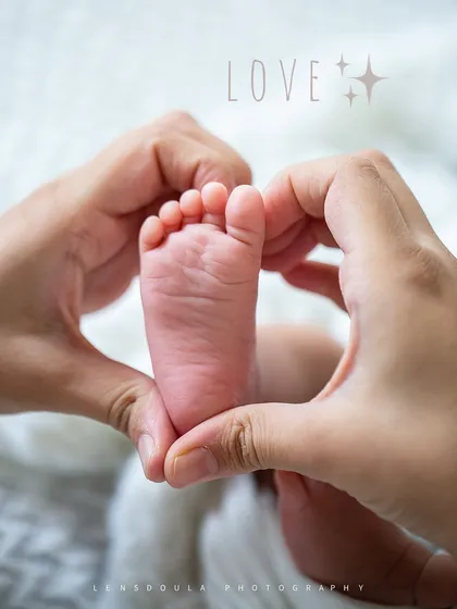 Two hands forming a heart around a tiny foot. This is a portrait of love, pure and simple.