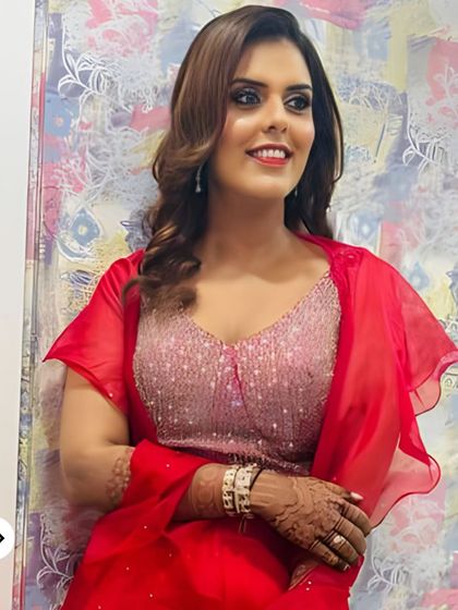 A bright and happy party look with glowing skin, a touch of shimmer on the eyes, and a vibrant red lip. The soft curls and red outfit create a festive and cheerful vibe.