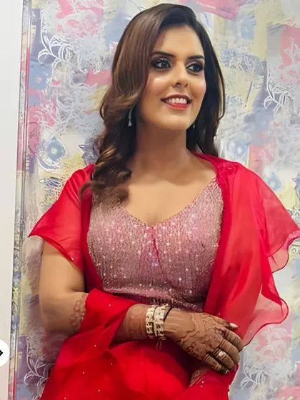 A vibrant and confident party look. The client's red outfit is paired with a bold smokey eye, contoured cheeks, and a glossy lip, making her ready for any celebration.