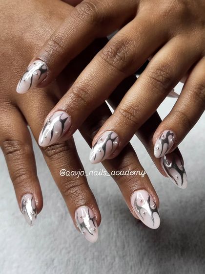 I love this dreamy combination of mirror chrome and blush tones. The abstract silver swirls on a soft pink base, accented with tiny rhinestones, create a look that is both classy and dramatic.