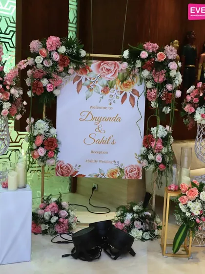 This personalized welcome sign for Dnyanda and Sahil is surrounded by a lush arrangement of roses, creating a warm and inviting focal point for their reception.