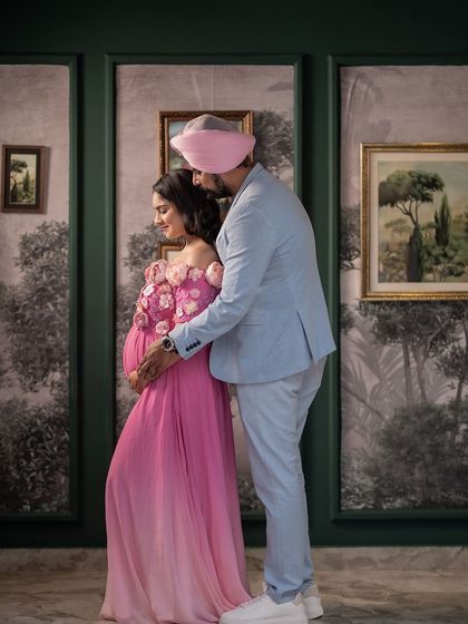 A quiet, stolen moment during a baby shower celebration. The father-to-be embraces his partner from behind, sharing a private look of love amidst the festivities.