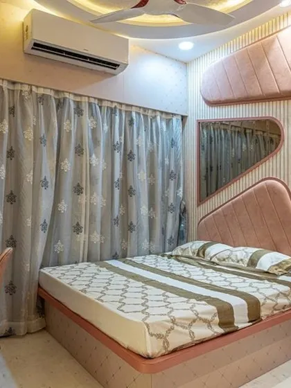 This playful bedroom design in Jogeshwari features an asymmetrical headboard and mirror arrangement in a soft pink. The integrated study unit makes it a perfect multi-functional space for a young adult.