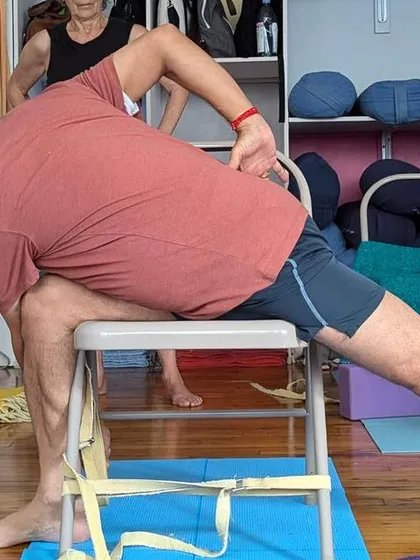 Demonstrating a variation of Parivrtta Parsvakonasana (Revolved Side Angle Pose) with a chair during a workshop in the US.