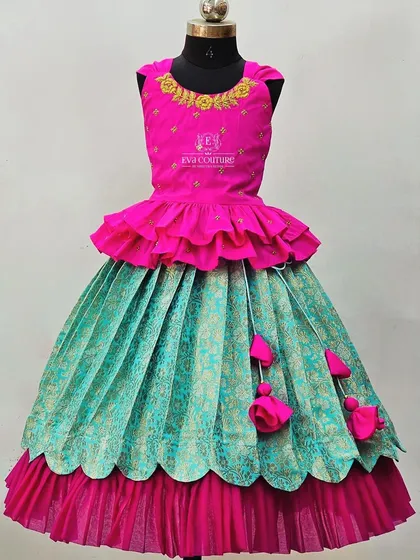 A modern layered gown in pink and teal. The skirt has a scalloped hem, and the sleeveless top has rose embroidery.